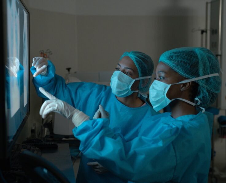 Diverse,Female,Surgeons,Looking,At,X-ray,Scans,In,Operating,Theatre